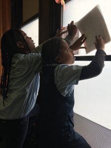 2nd graders tracing images on the windows to use as a light board